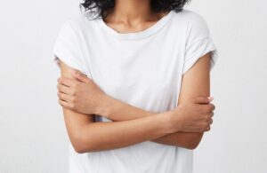 Indoor shot of beautiful happy African American student girl standing isolated in white studio smiling cheerfully, keeping her arms folded, relaxing indoors after morning lectures at university